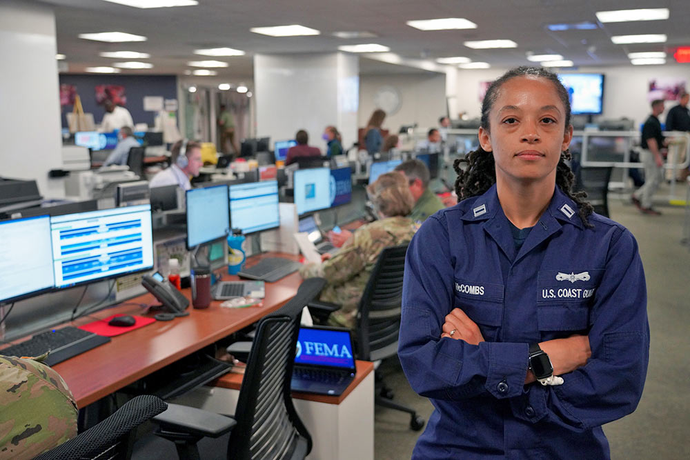 Woman stands in front of long rows of desks and computers.