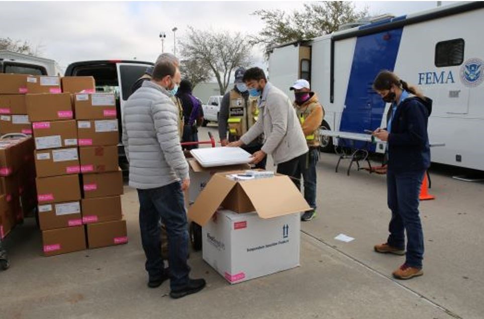 men unboxing the covid-19 vaccines outside in front of the fema trailer