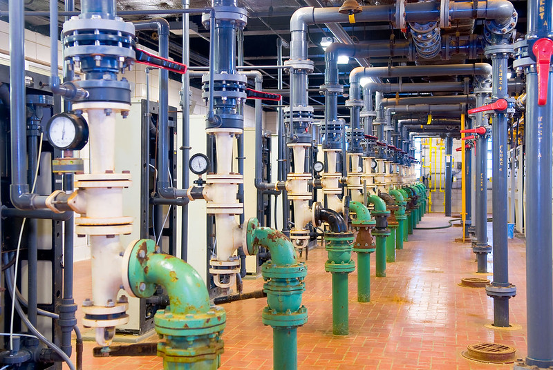Water treatment plant with workers wearing green coveralls.