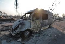  A van caught in the wildfire sits on a street. 