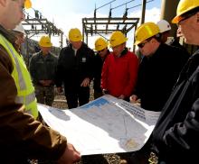  Federal officials and workers look at a map at a substation 