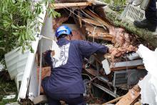 A search and rescue task for member kneels by a damaged structure.