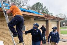 Incident Management Assistance Team members assist a resident of Baton Rouge as he places a tarp on his damaged roof.