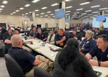 Groups of incident management assistance team members gather around tables to work through an hurricane readiness exercise. 