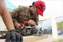 a female soldier cutting wood