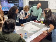 Group of six people looking a a map on the table.