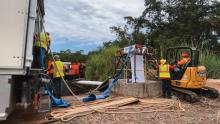 Four men with yellow and orange vests working on a sewer line