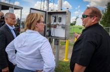 FEMA Administrator Deanne Criswell standing in between two men talking while looking at a dashboard outside