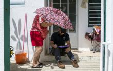 Survivor provides shade to FEMA Disaster Survivor Assistance staff while he helps her to apply for FEMA assistance in Barrio Candelaria, Toa Baja.