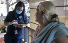 Empleada del equipo de Asistencia a Sobrevivientes de Desastres de FEMA ayuda a una sobreviviente en Juana Matos, Cataño, a llenar la solicitud de asistencia por desastre.