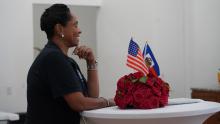 A woman smiling at a table with American & Haitian flag