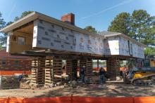 A picture showing a house under construction and being lifted by stilts.