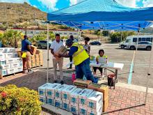 People handing out boxes under a tent. 