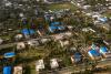  An aerial view of 3 square blocks of small homes. Many of them have blue plastic sheathing on the roof. 