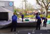 Four people in blue uniforms are setting up a medical station outside