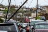 Downed utility poles on Smith Bay Road in Charlotte Amalie with card driving under it 